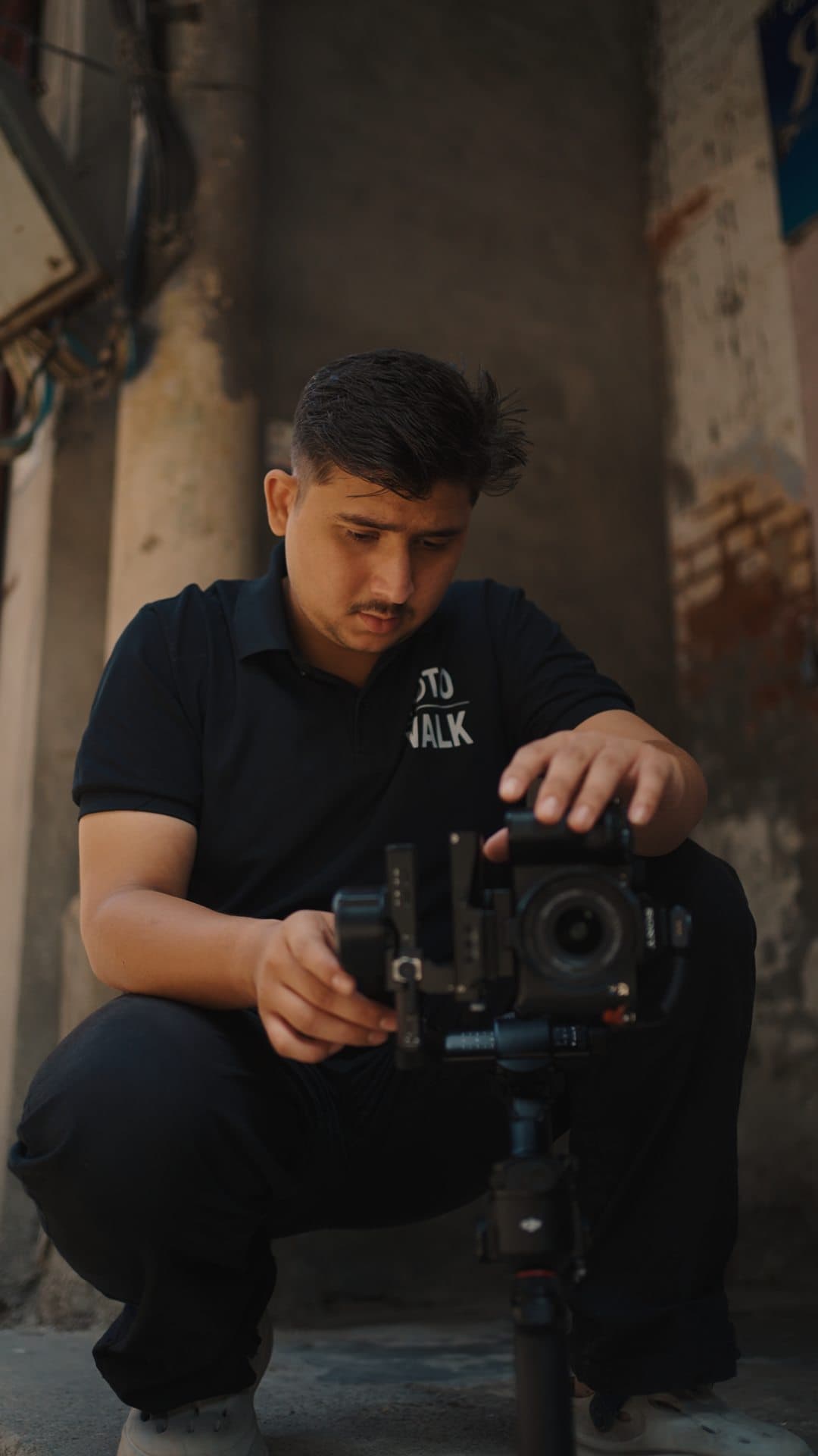 Crew member crouched in a doorway, adjusting a camera on a gimbal
