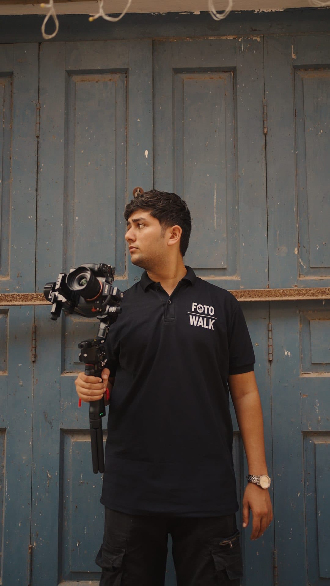 FotoWalk crew member holding a gimbal-mounted camera in front of a weathered blue door