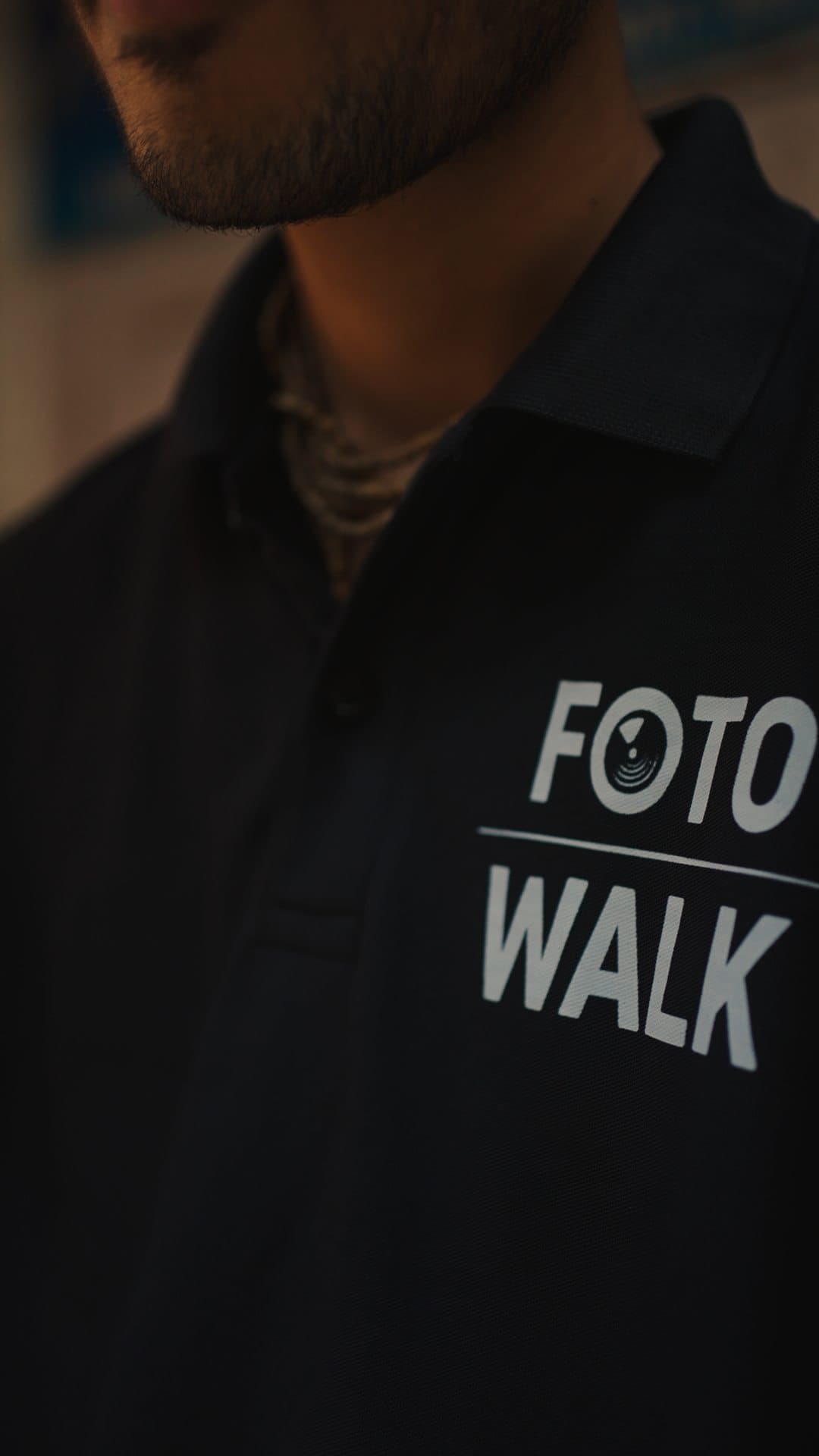 Close-up of the FotoWalk logo on a black polo shirt